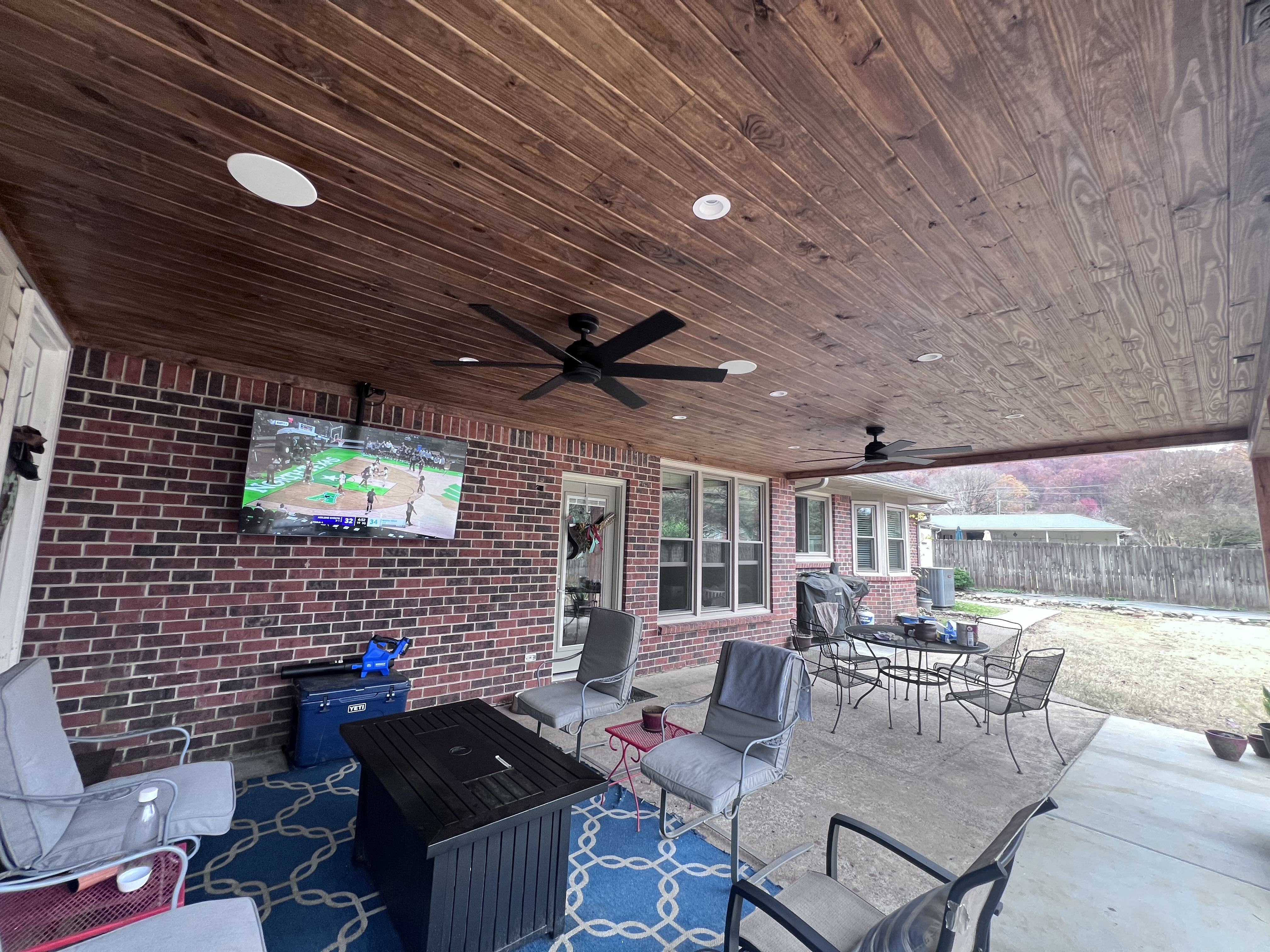 Under patio cover showing tongue-and-groove wood ceiling with fan